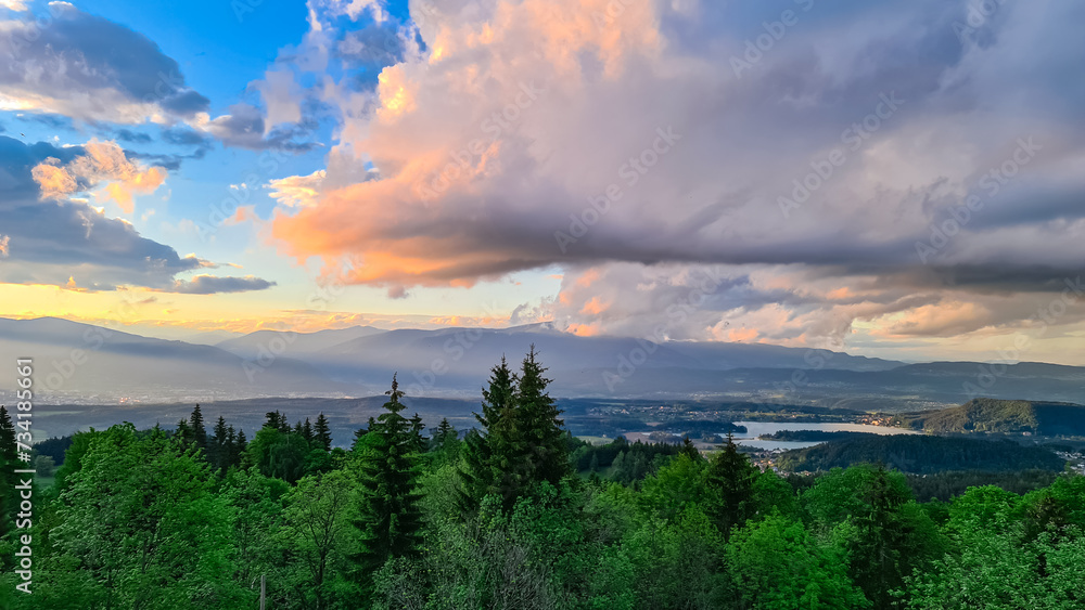 Obraz premium Scenic sunset view of Lake Faak seen from Altfinkenstein at Baumgartnerhoehe, Carinthia, Austria. Tranquil atmosphere on hiking trail in spring. Overlooking Villach area surrounded by Austrian Alps