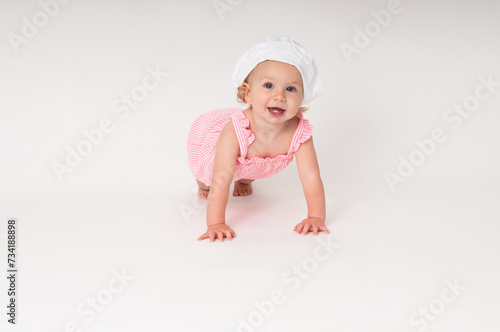 happy little baby girl crawling on the floor with white hat