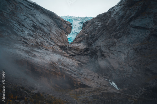 Tongue of the Briksdal glacier, Norway (Briksdalsbreen), on the rocks, with fog and clouds. photo
