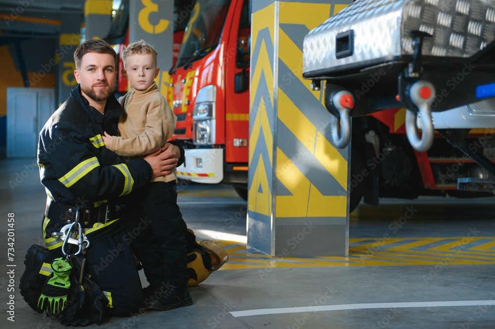 Obraz premium A firefighter take a little child boy to save him. Fire engine car on background