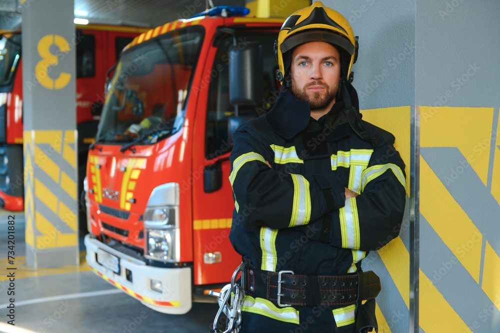 Naklejka premium Firefighters man in a protective suit near fire truck. Protection, rescue from danger. Fire station