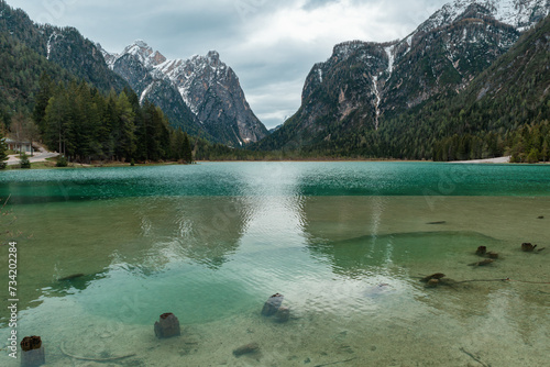 Alpine lake Lago di Dobbiaco in Dolomites mountains, Cortina dAmpezzo, Italy on moody spring day. Lake Toblacher See in the forest in Dolomiti in Italian Alps photo