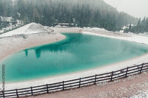 Heart shaped turquoise water alpine lake in Dolomites mountains, Cortina dAmpezzo, Italy in snowy spring day. Winter in spring with snow in Italian Alps