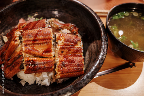 Unagi Don, Japanese grilled eel with teriyaki sauce serve with rice and Miso soup, on the counter in Japanese restaurant.