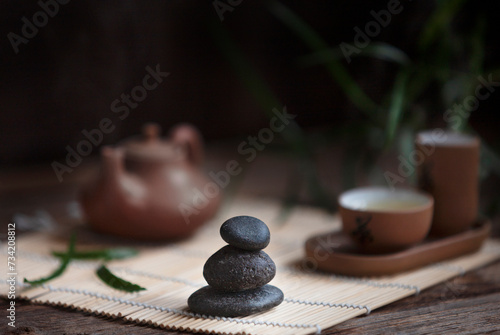 Traditional green tea ceremony set - white teapot and cups with stones piramide, house for the soul, on the tray photo