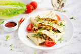Mexican Quesadilla wrap with chicken, corn and sweet pepper on white plate.