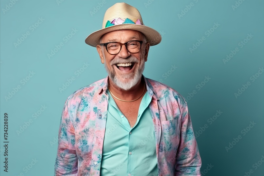 Handsome senior man with hat and glasses laughing against blue background