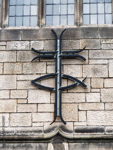 Christian symbol of cross and fish on church exterior wall, UK photo