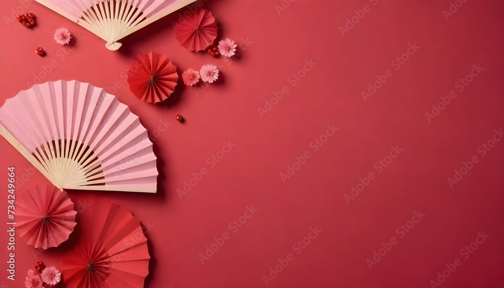 A collection of pink and red paper fans arranged with flowers and berries on a red background.