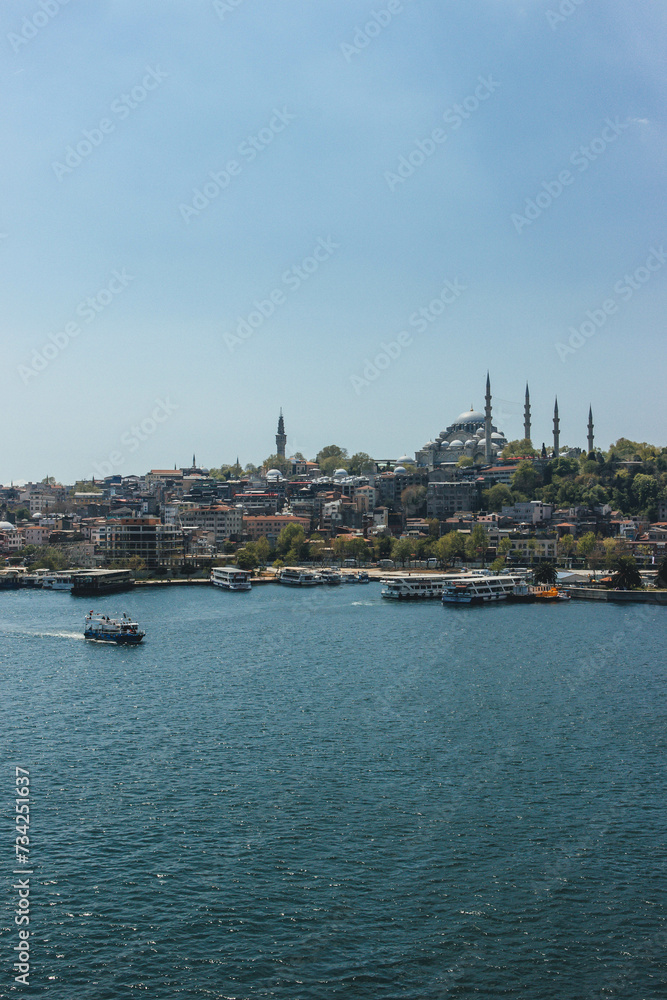 view of district galata tower in bosphorus strait magnific city istanbul with boats passing by and huge mosquee on top of hill