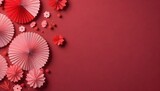 A collection of pink and red paper fans arranged with flowers and berries on a red background