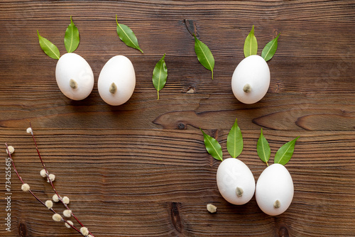 Fototapeta Naklejka Na Ścianę i Meble -  Easter and spring layout with bunnies made of eggs and green leaves with willow bud, top view