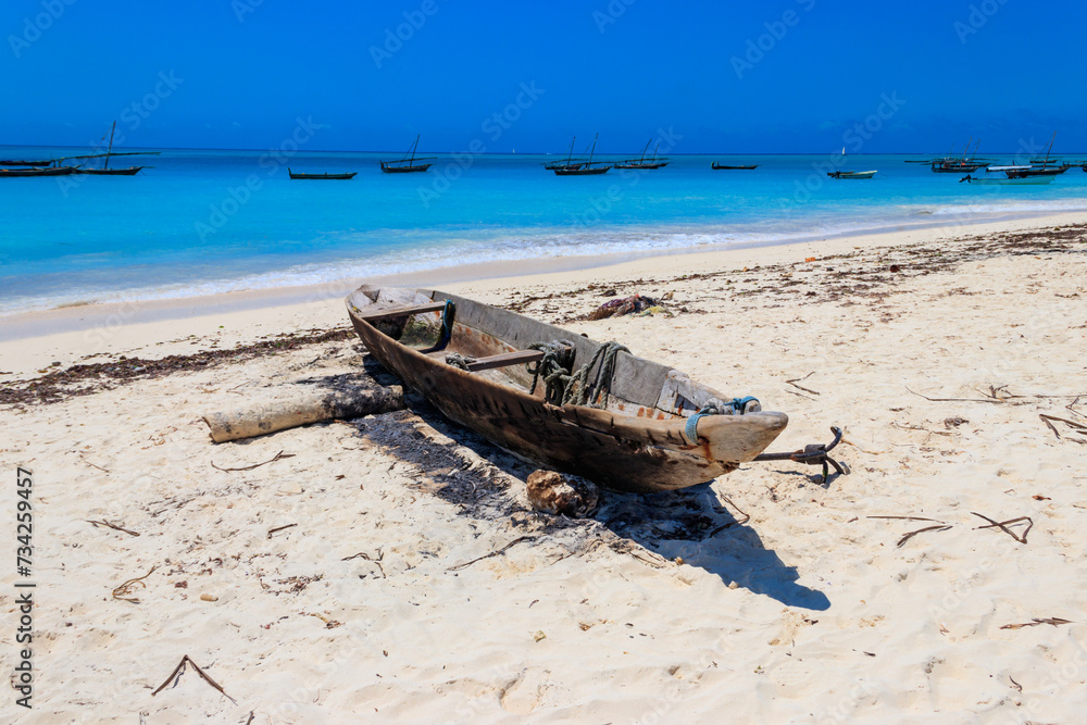 Old wooden boat ashore on tropical sandy Nungwi beach in the Indian ocean on Zanzibar, Tanzania Old wooden boat ashore on tropical sandy Nungwi beach in the Indian ocean on Zanzibar, Tanzania