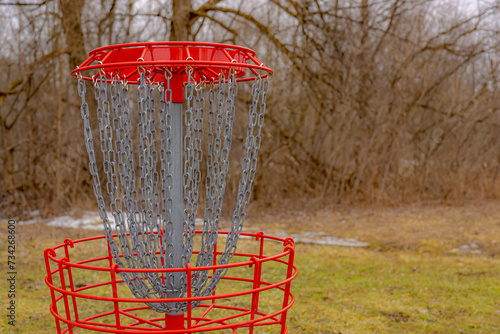 Red disc golf goal, net, pole hole, entrapment basket on a raw winter day. 