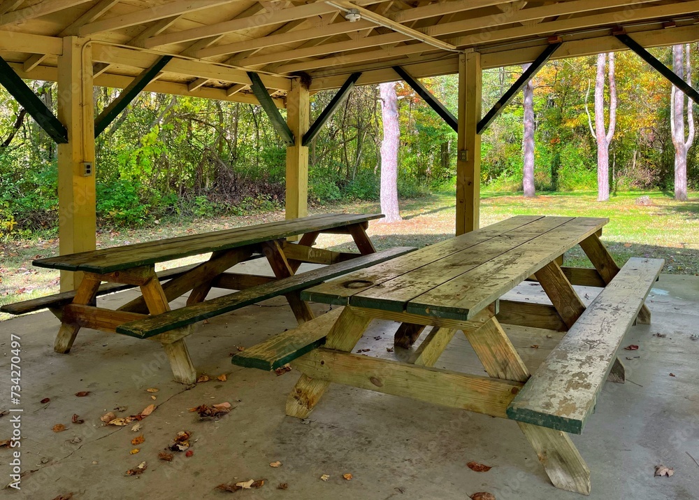 Wooden picnic tables under a shelter at a park