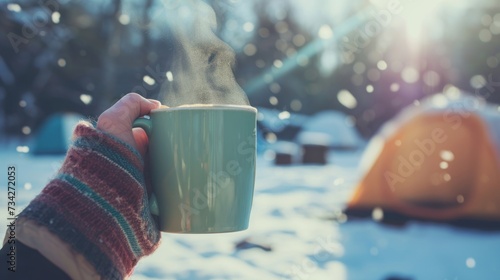 Close-up view of a hand holding a steaming hot coffee in cold winter.