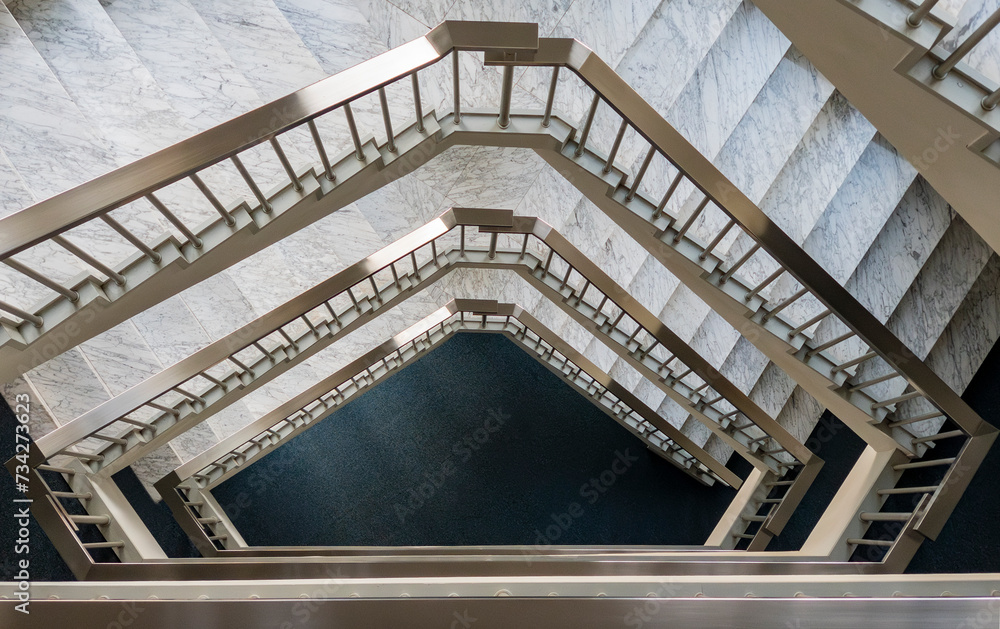 Obraz premium Geometric metal staircase with white marble treads in an office building