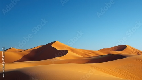  a large group of sand dunes with a clear blue sky in the background of a desert area.