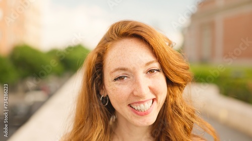Red haired woman looks at camera and smiles