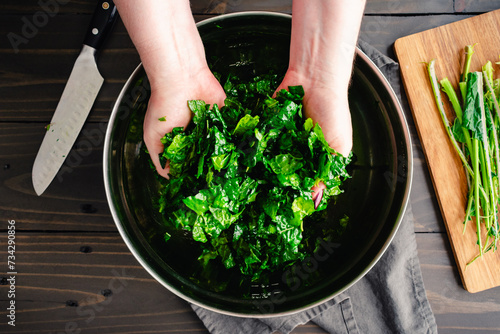 Massaging Chopped Tuscan Kale Leaves in Olive Oil: Hands holding chopped lacinato kale leaves massaged in extra virgin olive oil