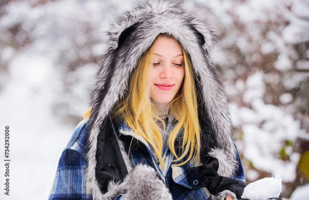 Wintertime. Blonde woman in plaid coat, fur hat and mittens with snowball in hands. Winter activities. Sensual girl in warm clothing playing with snow in park. Beautiful stylish woman in winter park. Wintertime. Blonde woman in plaid coat, fur hat and mittens with snowball in hands. Winter activities. Sensual girl in warm clothing playing with snow in park. Beautiful stylish woman in winter park.