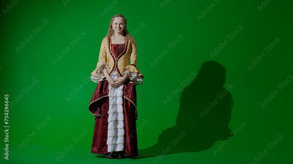Woman in ancient outfit on the chroma key green screen background. Female in renaissance style dress posing looking at the camera, smiling face.