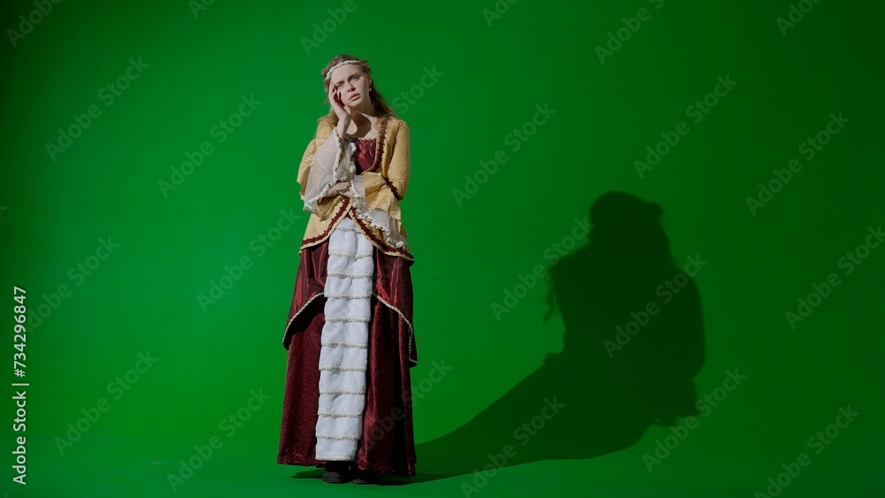 Fototapeta premium Woman in ancient outfit on the chroma key green screen background. Female in renaissance style dress posing looking at the camera, sad face.