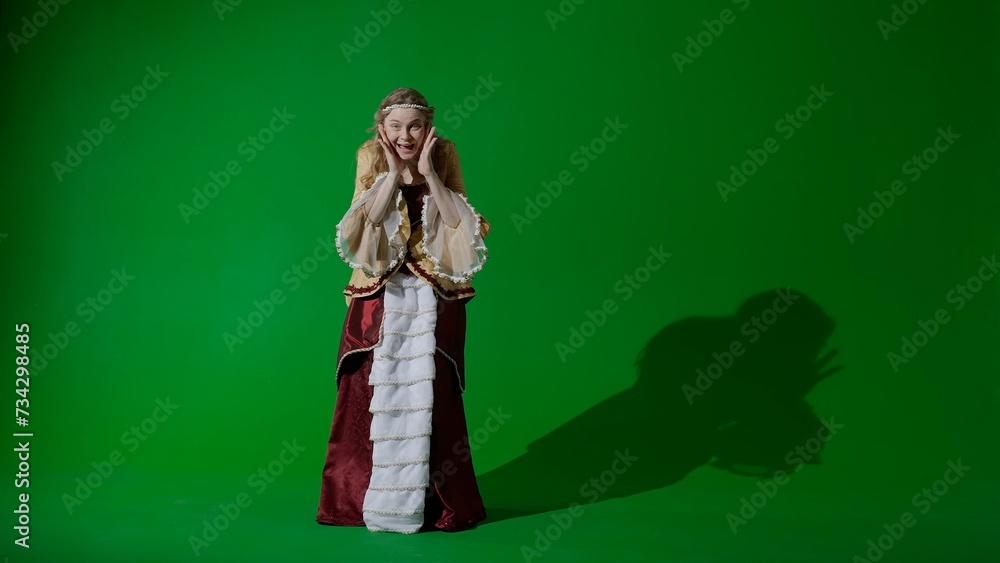 Fototapeta premium Woman in ancient outfit on the chroma key green screen background. Female in renaissance style dress looking at the camera, amazed surprised face.