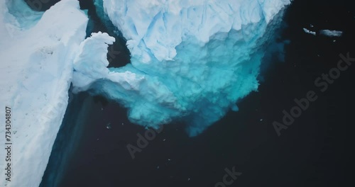 Antarctic iceberg underwater melting ice, global warming, ecology, climate change concept. Close up snow covered crashed glacier with cavity floating cold Polar ocean. Aerial 360 rotation panorama. photo