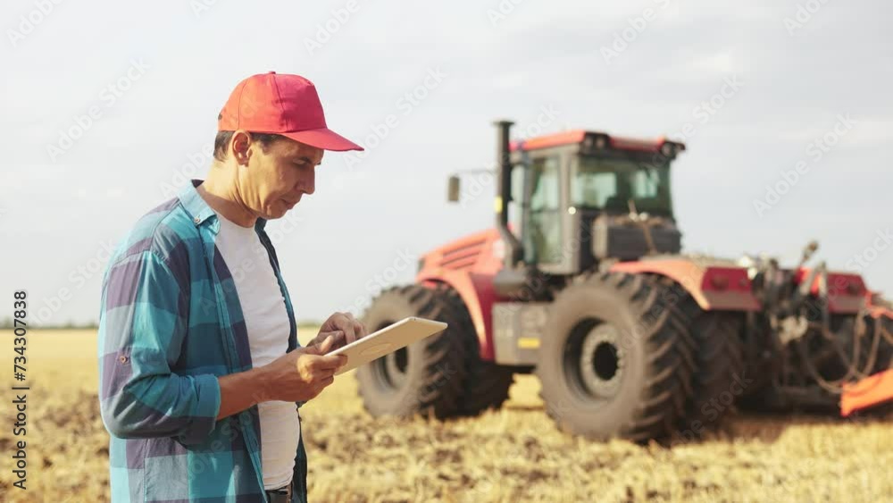 farmer in a wheat field. agricultural business concept. An experienced farmer walks through wheat field with a tablet in his hands next to combines. farmer lifestyle working in the field with wheat farmer in a wheat field. agricultural business concept. An experienced farmer walks through wheat field with a tablet in his hands next to combines. farmer lifestyle working in the field with wheat