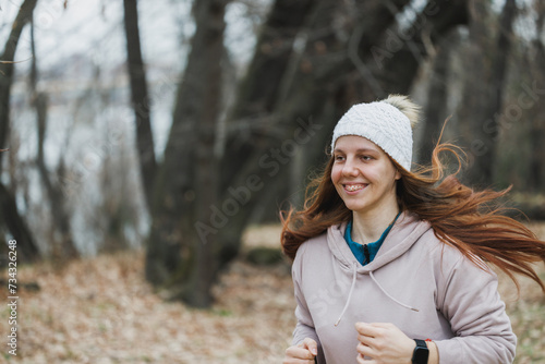 Woman Running Through Park With Tall Trees in Background