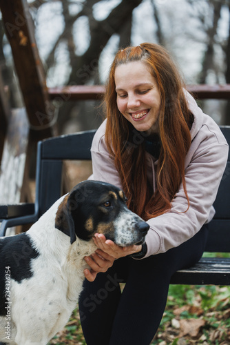 Woman Sitting on a Bench Petting a Dog in the Park