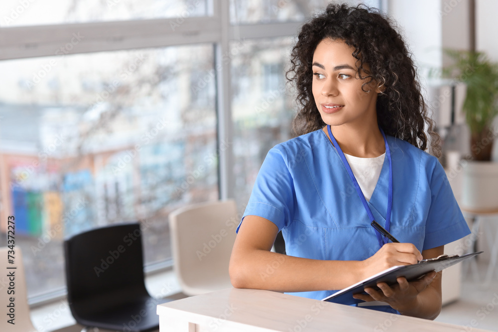 Female African-American medical intern writing in clipboard at hospital Female African-American medical intern writing in clipboard at hospital