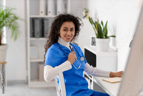 Female African-American medical intern sitting at table in clinic