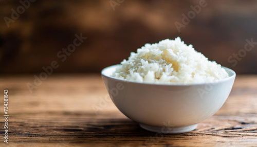 Cooked rice in bowl on wooden background, symbolizing nutrition, sustenance, Asian cuisine. Copy space for food-related concepts