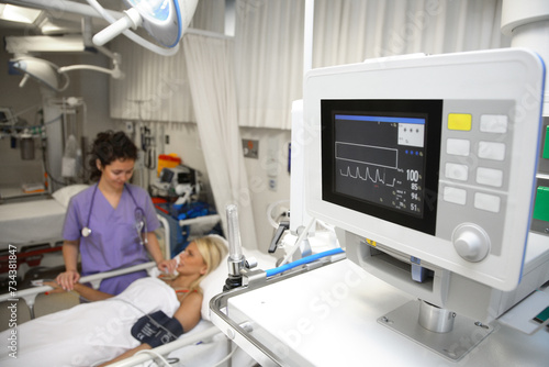a doctor, nurse giving medical treatment at the bedside of a female patient in intensive care in a hospital. close-up of the patient's vital signs on the screen photo
