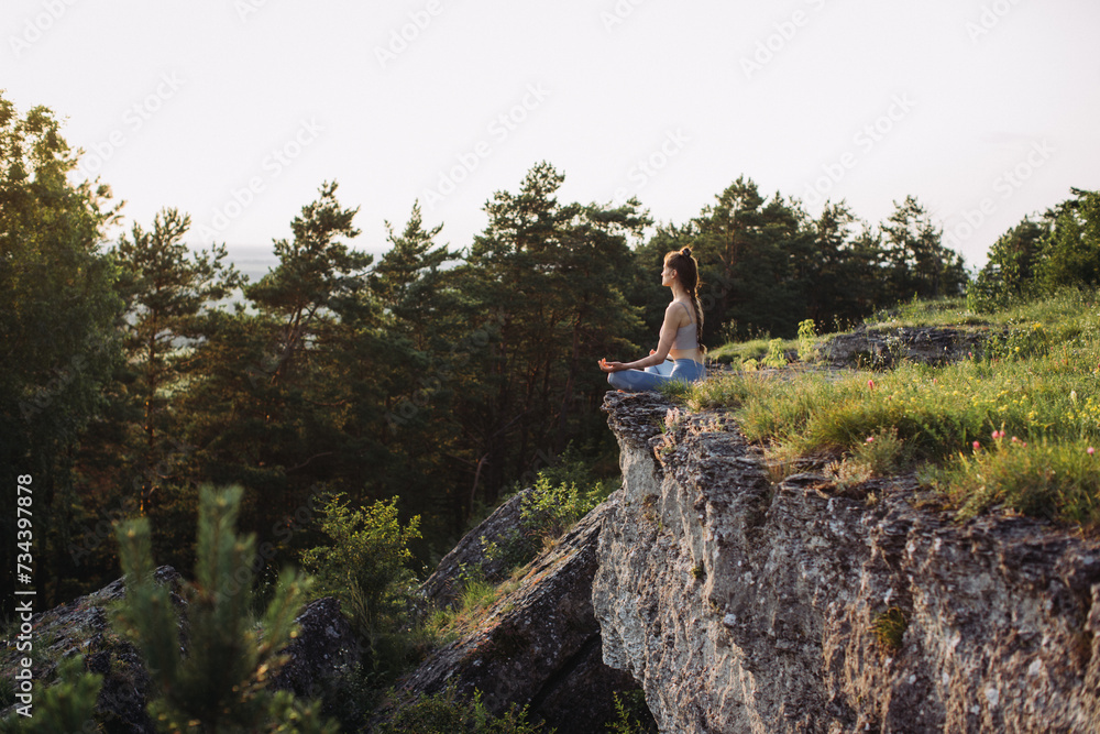 Young woman practicing yoga at sunset in a beautiful mountain location.