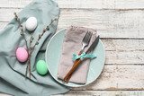 Beautiful festive table setting for Easter with eggs and willow branches on light wooden background