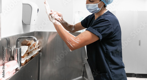 Surgeon having her hands surgically washed. A Caucasian doctor dressed in his right-hand profile with her hands full of foam and dressed in her surgical uniform.  photo