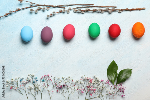 Painted Easter eggs, gypsophila flowers and willow branches on light background