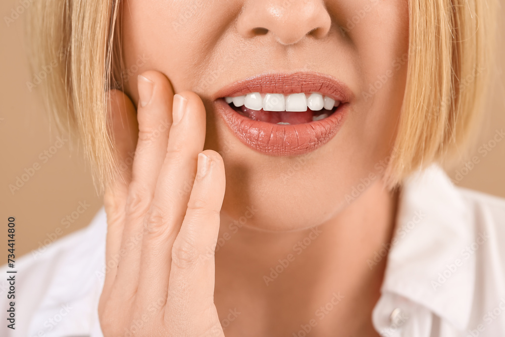 Obraz premium Beautiful mature woman suffering from toothache on brown background,closeup