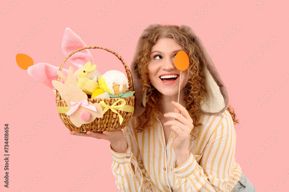 Beautiful young happy woman in bunny ears with Easter basket on pink background Beautiful young happy woman in bunny ears with Easter basket on pink background