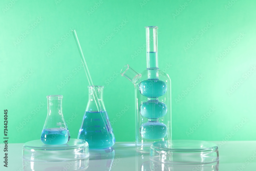 Laboratory analysis. Different glassware on table against green background Laboratory analysis. Different glassware on table against green background