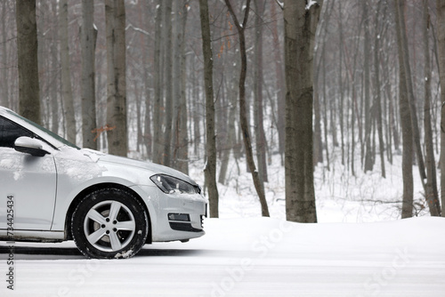 Car with winter tires on snowy road in forest  space for text
