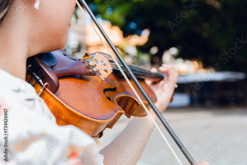 Close-up of unrecognizable busker woman playing violin outdoors.