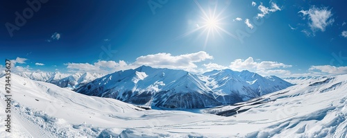 View of snowy mountains with clear blue sky and white clouds in winter