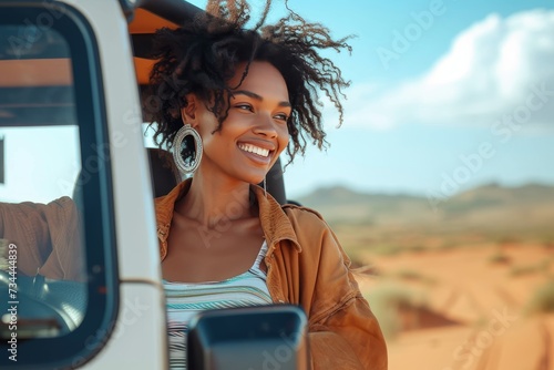 A carefree woman radiantly smiles while driving through the vast desert landscape, her face reflected in the car's mirror, as she enjoys the freedom of the open road and the endless sky above