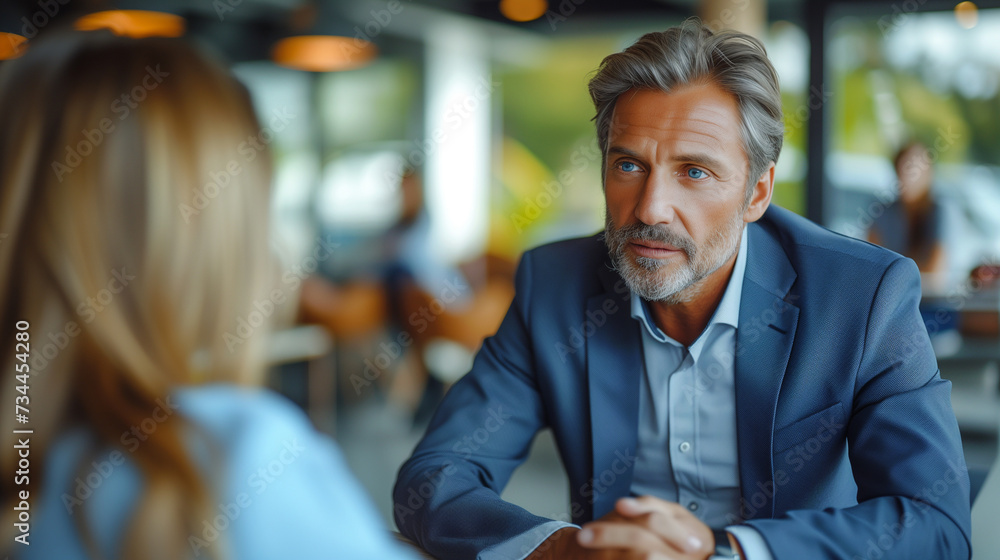 Fototapeta premium Happy middle aged professional business man executive hr or bank manager, lawyer or financial advisor having job interview or business conversation consulting client