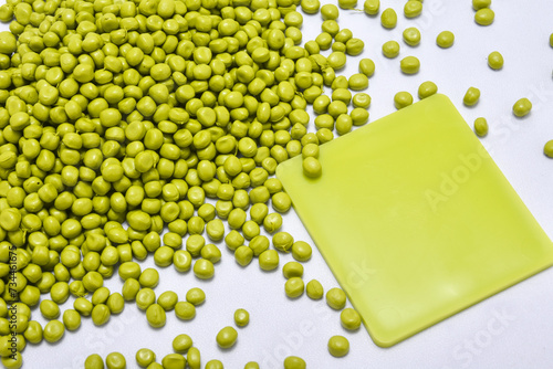 Guacamole color masterbatch granules on a white background,coloring polymer for products in the plastics industry,equipped with a color chip as an example color produced