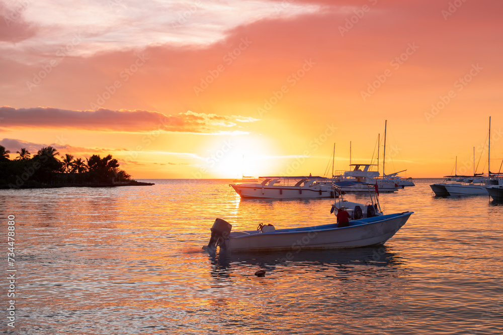 Sunset scene at the ocean bay with many yachts and water taxi boats moored by the shore.